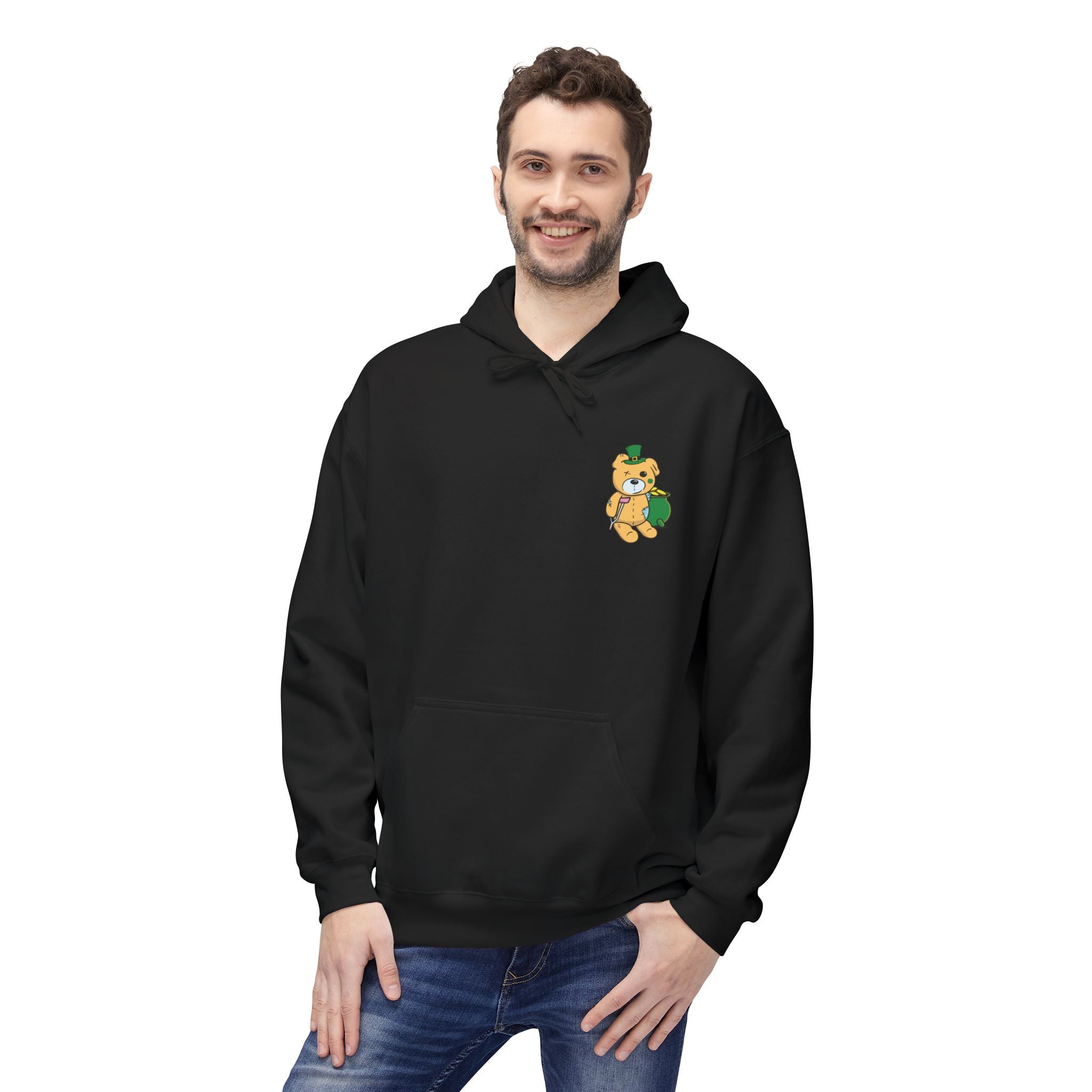 A person stands smiling with one hand in their jeans pocket, wearing Printify's "Who Needs Luck Hoodie"—a black sustainable hoodie featuring a small teddy bear graphic.