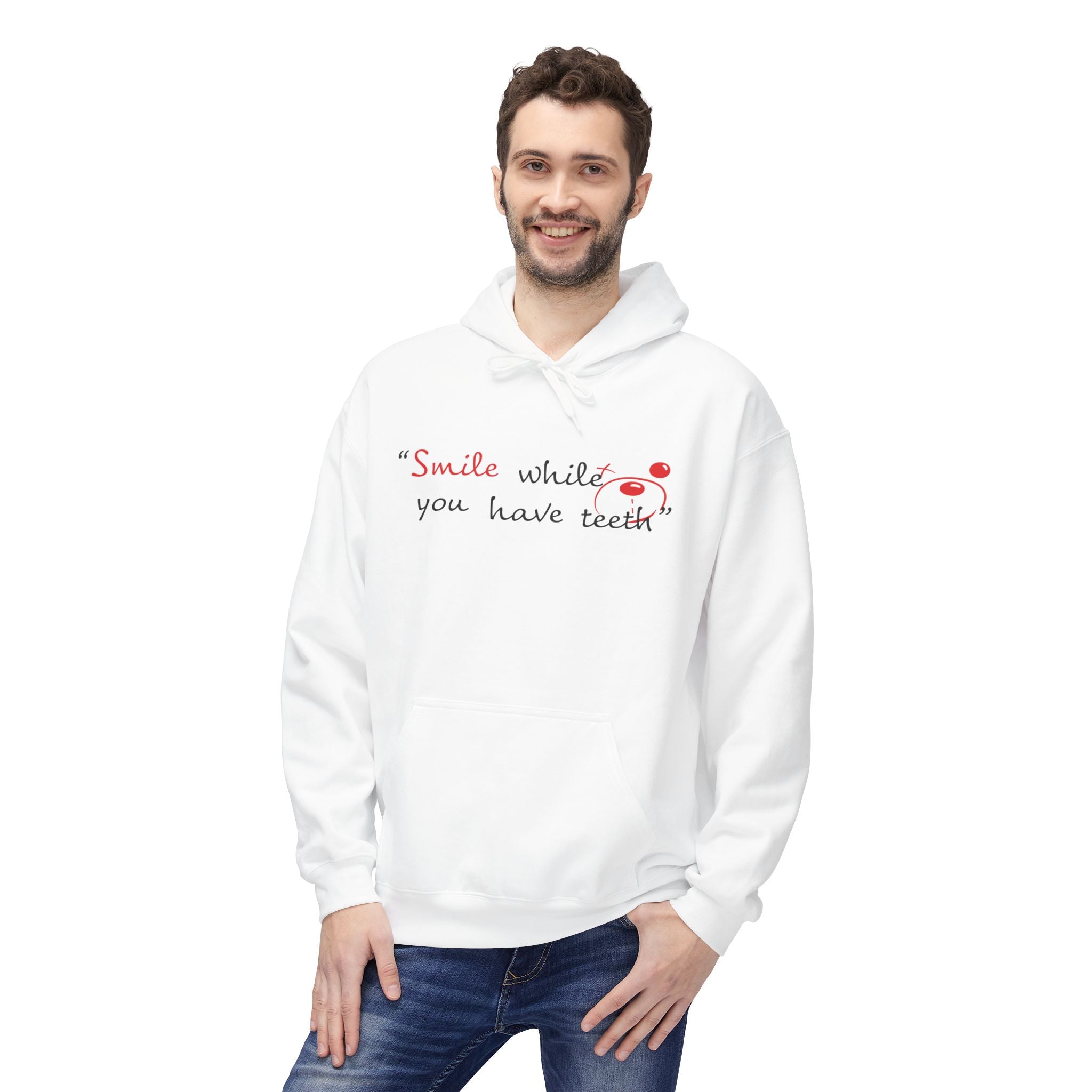 A man smiles in a WRAP-certified Printify Just Smile Hoodie, featuring "Smile whilst you have teeth" printed on the front in black and red letters.