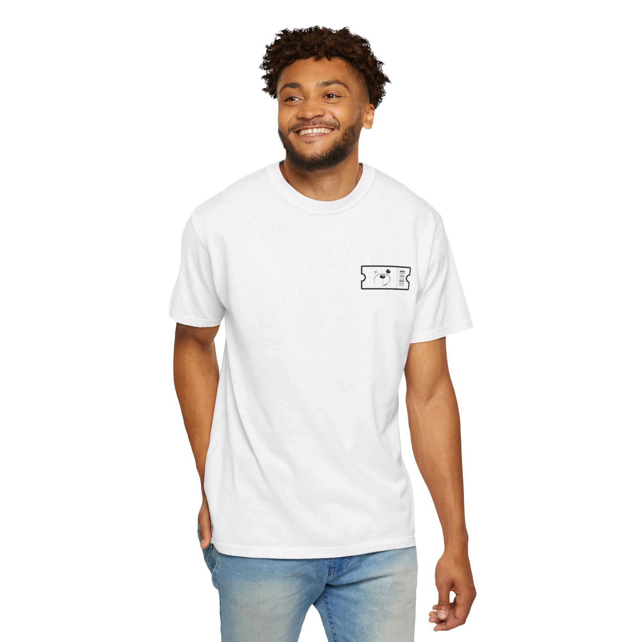 A man wearing the Buy The Ticket Tee by Printify, featuring a small cartoon face design on the chest, crafted from 100% U.S. cotton, stands against a plain white background.