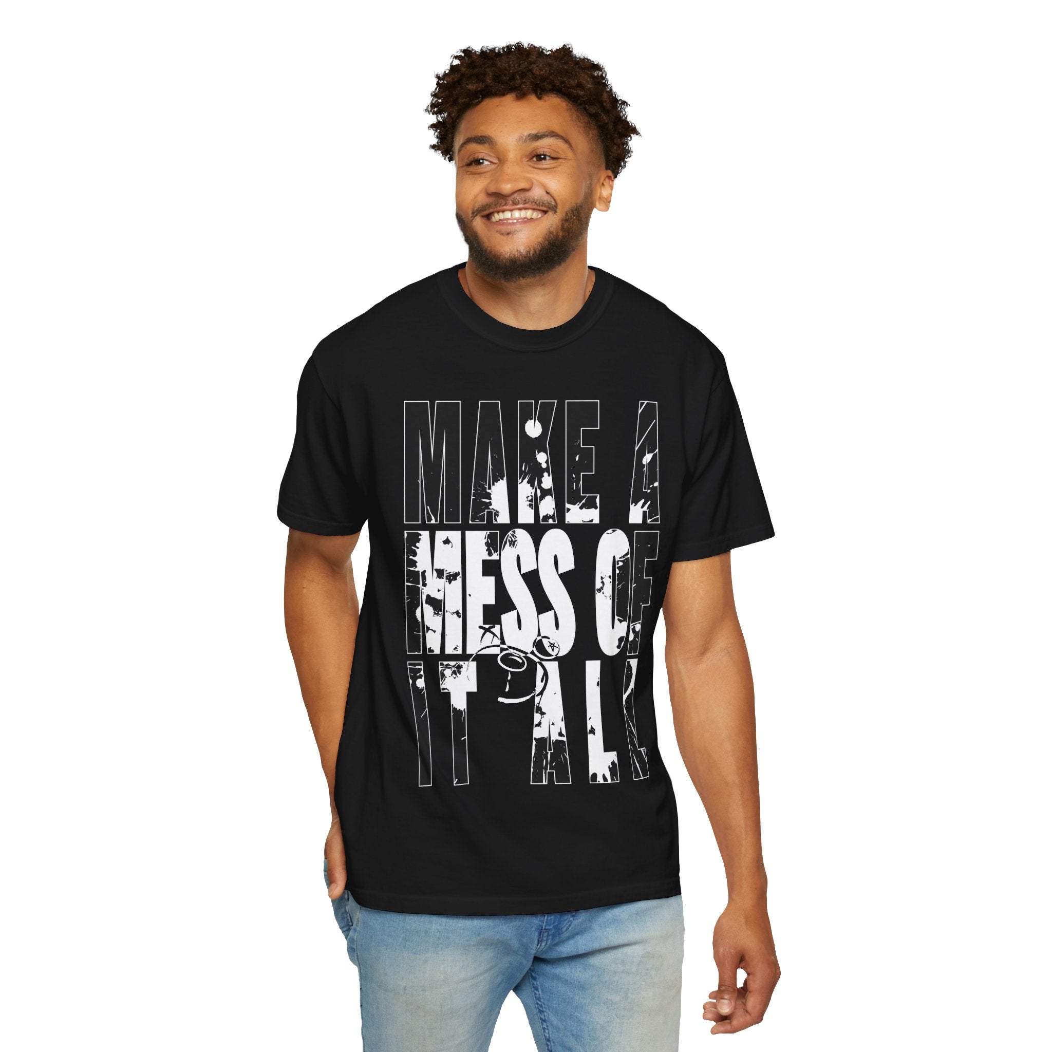 A man wearing a Printify Make A Mess Tee, crafted from soft US cotton and featuring the bold text "Make a Mess of It All," smiles while standing against a white background.