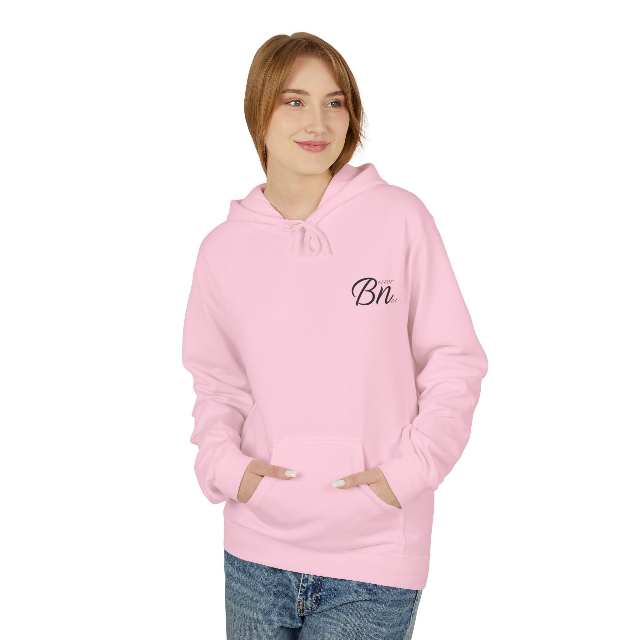 A person wearing an ethically made pink "The Script Hoodie" from Printify stands with hands in pockets against a plain white background.