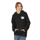 A person stands with hands in pockets wearing the black Graffiti Bear Hoodie by Printify, an eco-friendly, WRAP-certified product made from ring-spun cotton featuring a white abstract design against a plain background.