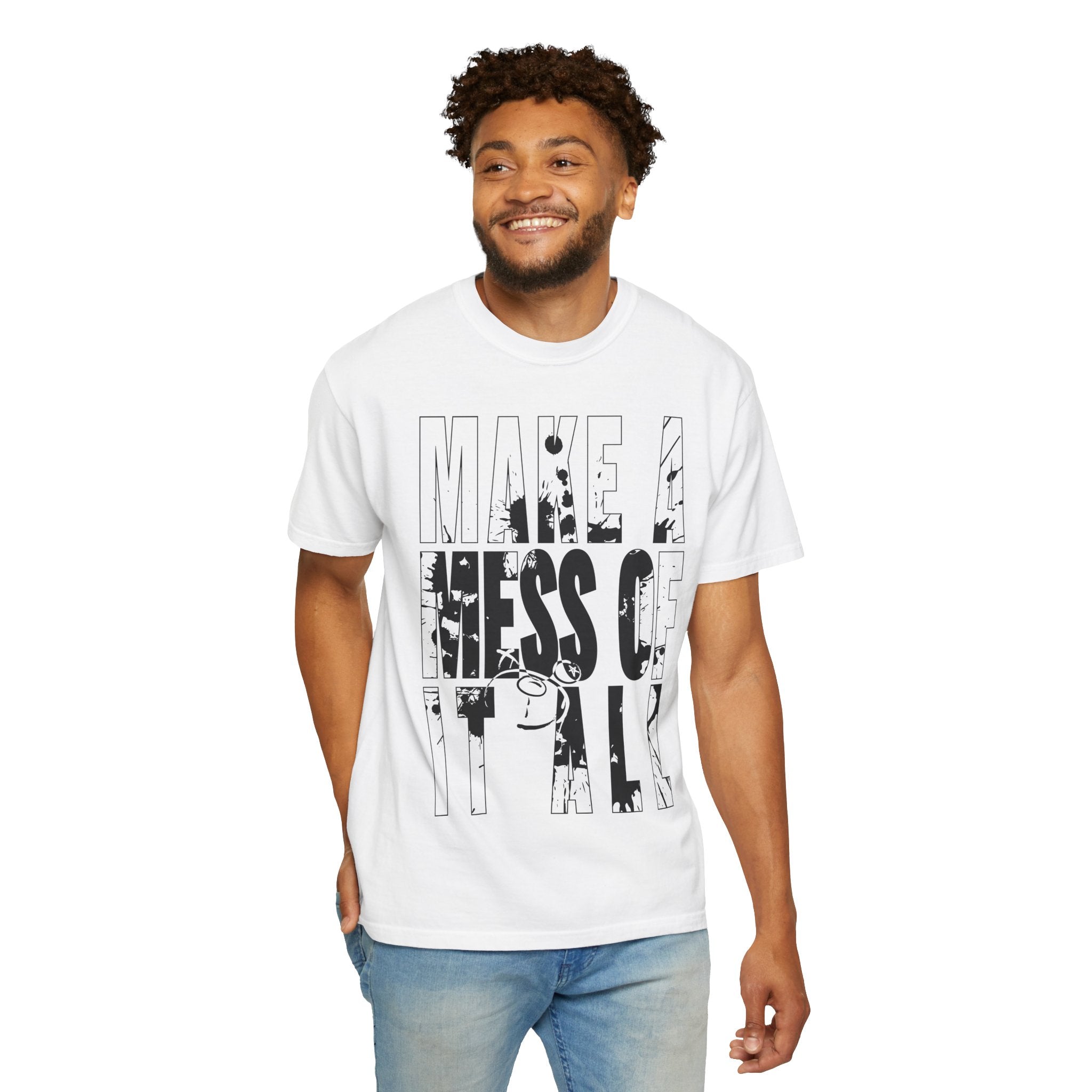 A man stands smiling in a relaxed fit Make A Mess Tee by Printify, crafted from soft US cotton, with black text reading "MAKE A MESS OF IT ALL.