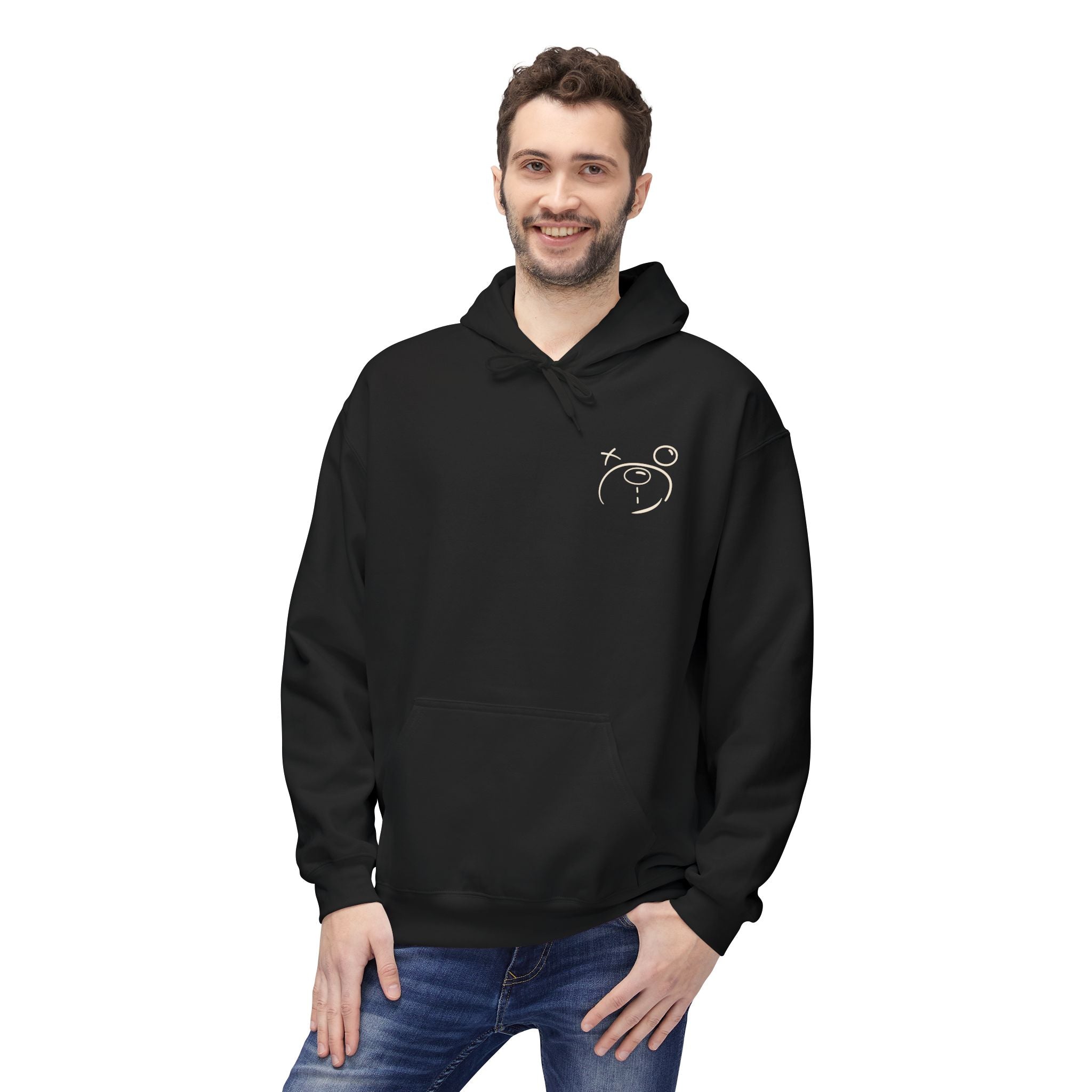 A man is smiling while wearing the Have Fun Be "Safe" Hoodie v3 by Printify, featuring an eco-friendly design with a minimalist face on the chest, and has one hand in his jeans pocket.