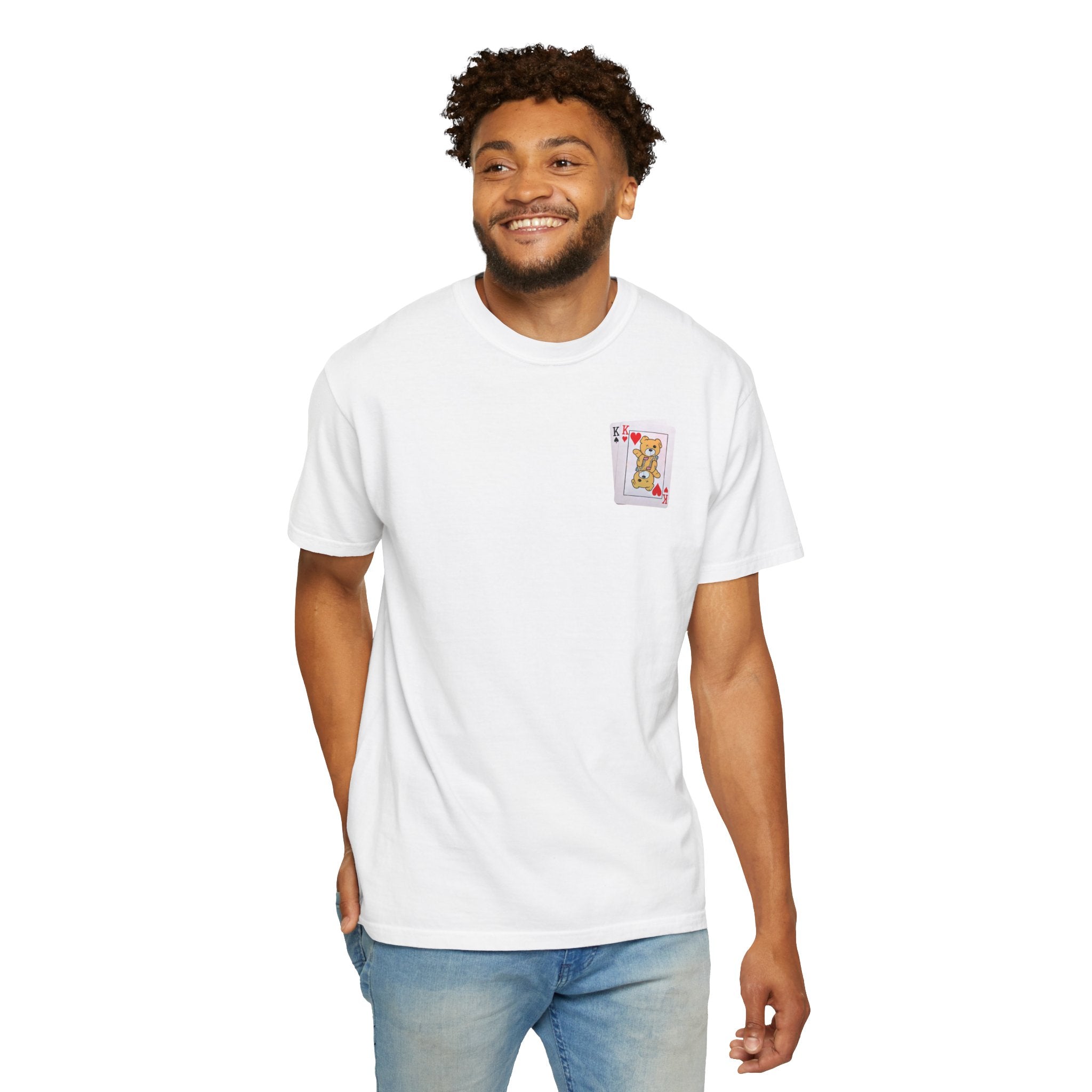 A man smiles in a "Bet on Better not Tee" by Printify, featuring a playing card design on the pocket. Made from 100% US cotton, this white Comfort Colors premium t-shirt pairs seamlessly with his blue jeans as he stands against a plain white background.