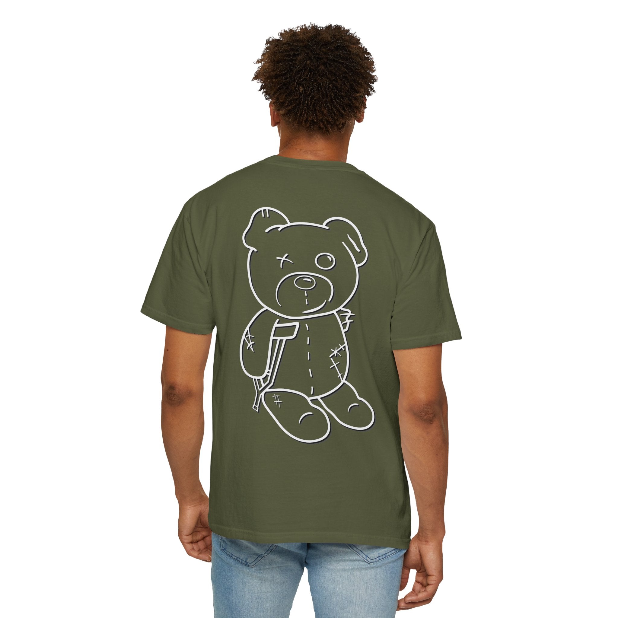 A man wears the Printify Mascot Tee, crafted from garment-dyed fabric with a teddy bear graphic on the back. This green T-shirt, made from US cotton, pairs perfectly with light blue jeans.