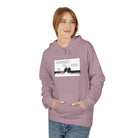 A person in a "Live Young Hoodie" by Printify, purple with text and image design on the front, hands in pockets, wearing jeans, and smiling slightly. This eco-friendly hoodie embodies sustainable fashion through ethical manufacturing practices.