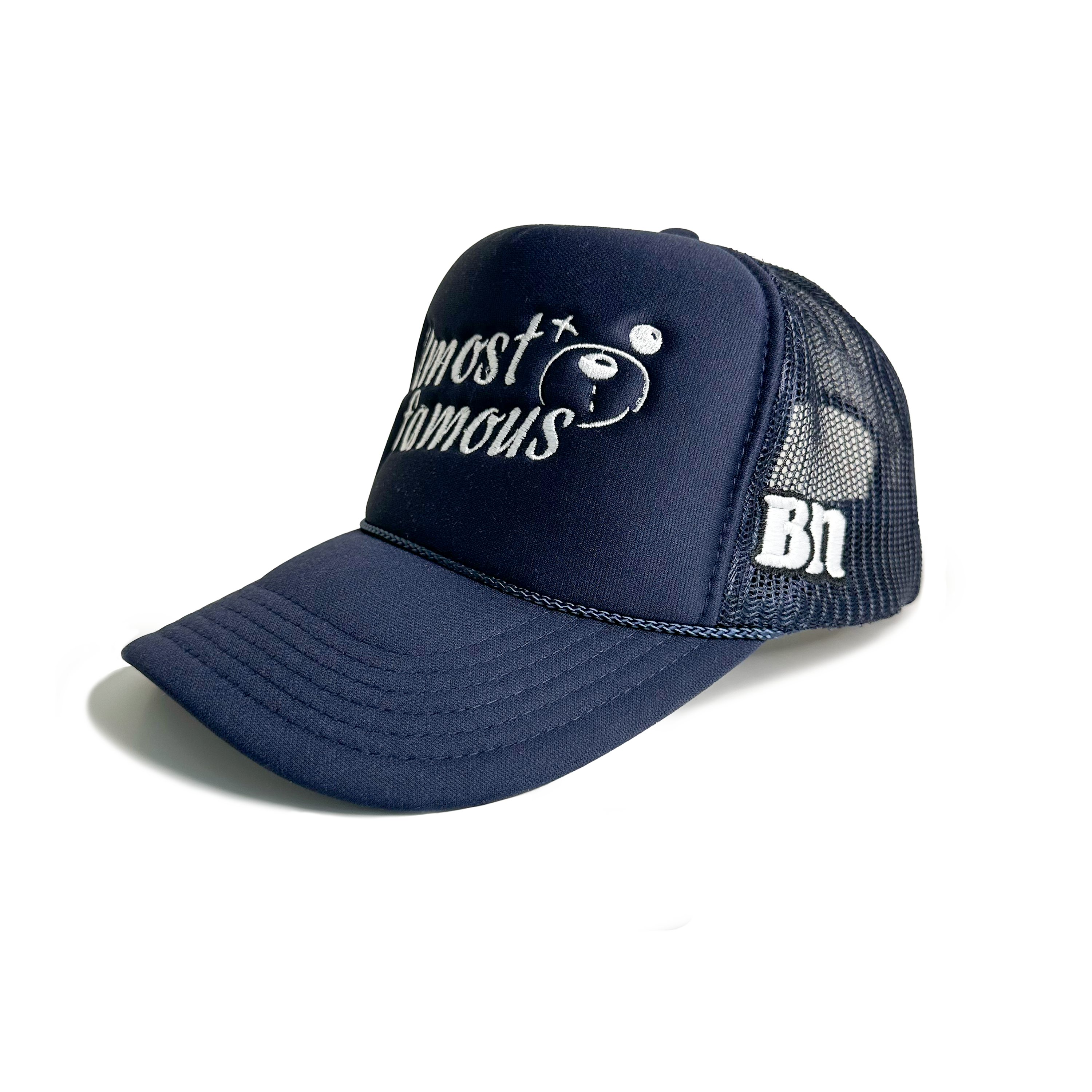 The "Almost Famous Trucker" from Better not is a dark blue, high-crown fit snapback hat featuring "Almost Famous" embroidered on the front. It includes a small design and the initials "Bn" on the side. Known for its stylish embroidered placements, this hat is available with next day shipping.