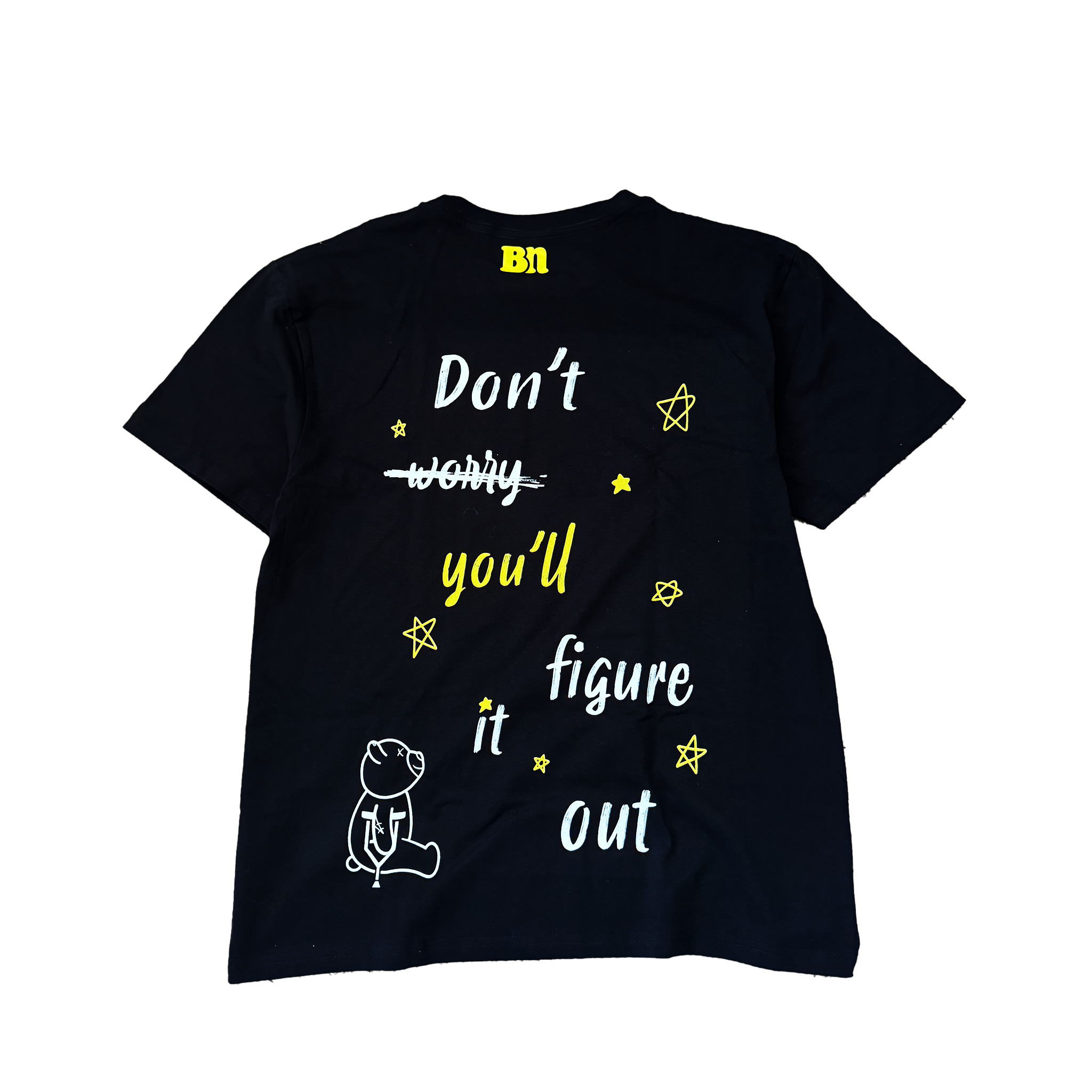 An oversized black Don't Worry Tee by Better not with yellow text that reads "don't worry, you'll figure it out," accompanied by stars, lines, and an illustration of a sitting bear.
