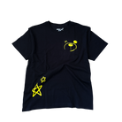 Better not's Don't Worry Tee, an oversized t-shirt made of 100% cotton jersey in black color, featuring a yellow cartoon face and two star symbols on the front, is lying flat on a light-colored carpet.