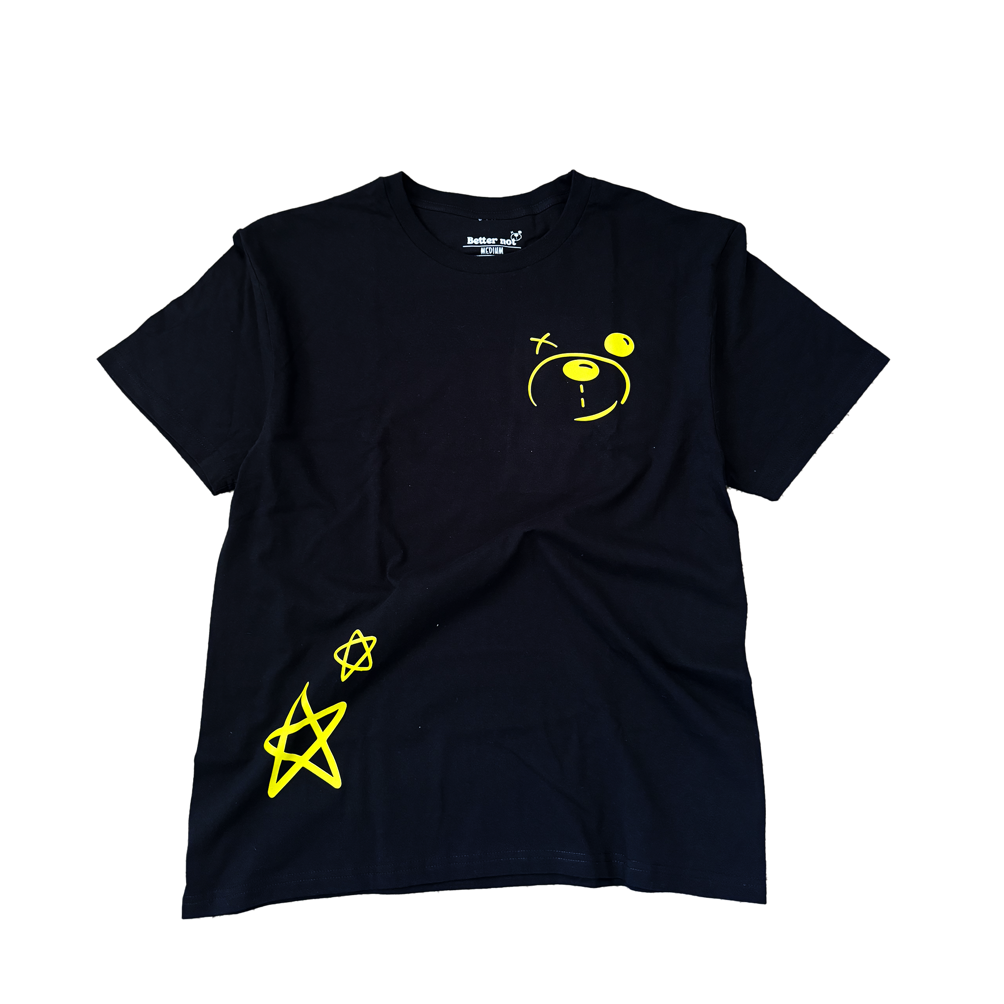 Better not's Don't Worry Tee, an oversized t-shirt made of 100% cotton jersey in black color, featuring a yellow cartoon face and two star symbols on the front, is lying flat on a light-colored carpet.