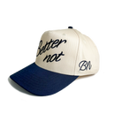 Introducing "The Classic" by Better not—a stylish baseball cap featuring a light cream and dark blue design. It boasts "Better not" intricately 3D embroidered on the front, with "BN" on the side, and is completed with a convenient snapback closure.